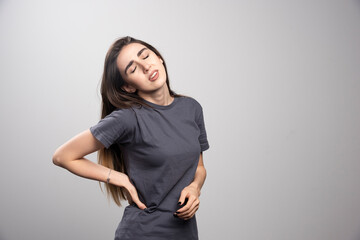 Young woman standing and touching her back