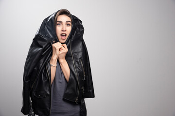 Model wearing black leather jacket over a gray background