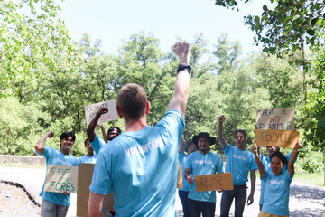 Group of volunteer protest against earth pollution and global warming. Back of head leader standing and raising fists up to cheer up and motivate team to do charity work and save our planet.