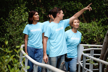 Group of volunteers in blue t-shirt exploring forest for data store, doing charity work together with team, reduce pollution environmental problem, prevent global warming and climate change.