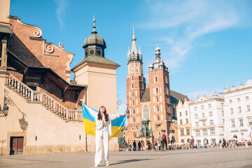 Obraz premium woman covered with ukrainian flag at the center of poland Krakow city