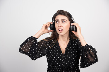 Young woman model listening music in headphones on a white background