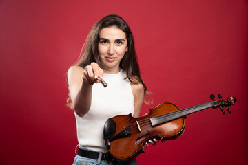 Young beautiful woman holding a violin on a red background