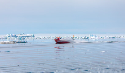 Fast moving motorboat trying to get out of the ice - Stranded icebergs in the fog at the mouth of the Icefjord near kulusuk, Greenland