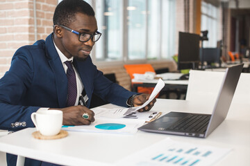 Portrait of an African American in the office. Black man in a business suit working on a laptop