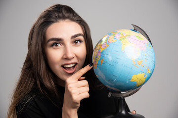 Surprised woman pointing at small country on globe