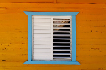Rustic blue and orange wooden house with wooden window shutters. Dominican Republic.