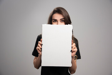Naklejka premium Young artist in black shirt hiding behind canvas