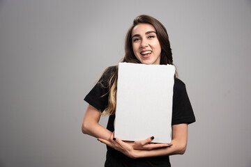 Young woman with happy expression holding canvas