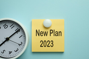 New Year,action plan,business target Concept.,New Plan 2023 word on yellow sticky note with white clock over blue pastel background with copyspace.