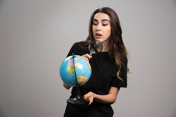 Young woman looking at globe with magnifying glass