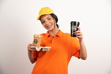 Smiling woman courier giving two cups of coffee