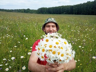 A man collects a bouquet of flowers in a meadow.