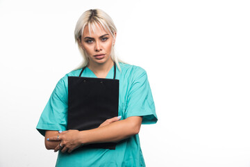 Obraz premium Female doctor holding a clipboard on white background looking serious