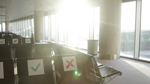 Airport during the Covid-19 pandemic. The rising sun in the morning illuminates the empty departure and waiting area from a chair with special social distancing signs