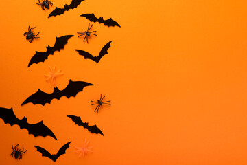Orange Halloween background. Flock of black bats for Halloween. Black paper bat silhouettes on orange background. Halloween concept, Copy space, top view, overhead.