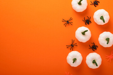 Orange Halloween background. Flock of black bats, spider, pumpkin, skeleton and leaves for...