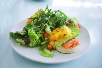 Eggs Benedict on english muffin with smoked salmon and fresh salad on table in restaurant.