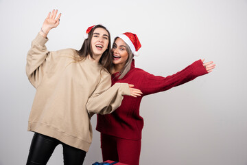 Attractive and smiling women in t-warm sweaters looking at camera isolated on white