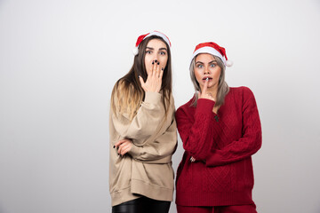 Photo of confused women friends posing isolated over white wall background