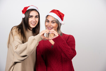 Two young women doing heart symbol gesture and laughing