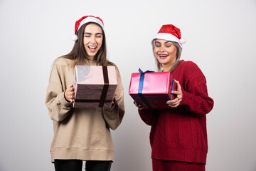 Two smiling girls in Santa hat holding festive Christmas presents