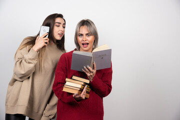 Girl in red sweater reading a book near another girl