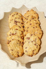 Cookies baked with chocolate chips. Directly above macrophotography of a plate with overhead view of the fresh biscuits with direct sunlight and shadows.