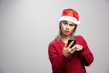 Angry woman in red sweater holding cellphone and looking at camera