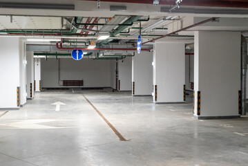 Empty underground parking of a residential building or garage interior with markings and road signs.