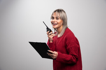 Female businesswoman talking with radio transceiver on gray background