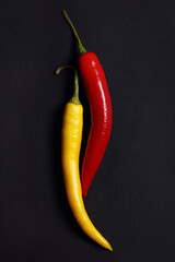 Red and yellow chili peppers on black background. Food photography