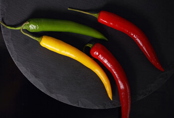 Colorful chili peppers on black background. Food photography