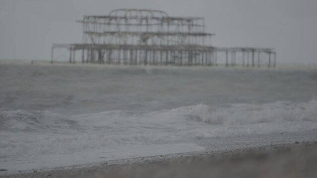 Waves crashing against stony beach with the West Pier, Brighton