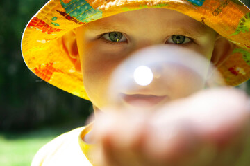 Little boy with soap bubbles in summer park.