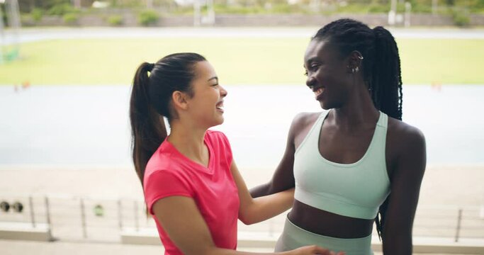 Two happy female athletes greeting each other at a sports ground. Portrait of positive athletic fit sportswoman meeting at a stadium. Active friends embracing and hugging outdoors after exercising