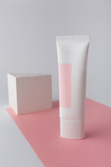 White cosmetics cream tube on pink background template, mock up, no brand. Face skin anti aging care. Concrete decor. Copy space.