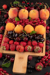 Different ripe fruits on a wooden board on a dark table. Fruit background.