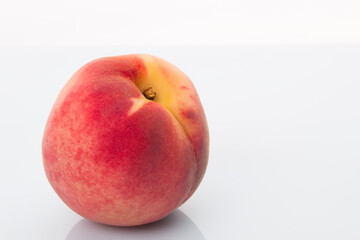 A bright red peach on a white background
