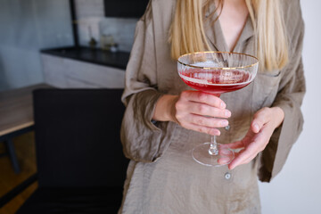 A glass of red wine, champagne or a cocktail in the hands of a girl relaxing. Tasting of alcoholic beverages. Summer rest. Romantic evening aperitif. Close-up of a glass of wine
