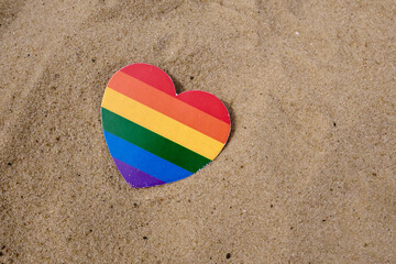 Rainbow heart made of paper lies on the sand. LGBT flag. LGBTQIA Pride Month in June. Lesbian Gay Bisexual Transgender. Gender equality. Human rights and tolerance. Rainbow flag 
