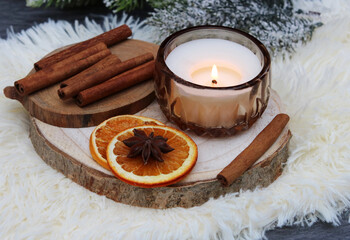 Obraz na płótnie Canvas Aromakerze mit Weihnachtsduft auf einer Holzscheibe mit Zimtstangen und Orangenscheiben.