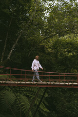 Man tourist on a bridge in the tropical jungle.