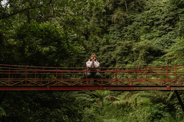 Man tourist on a bridge in the tropical jungle.