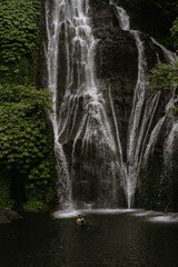 People swim in a mountain waterfall, Bali, Indonesia.