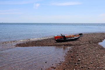 Three canoes rest on the edge of the shingle beach at the mouth of the river Axe in Axmouth
