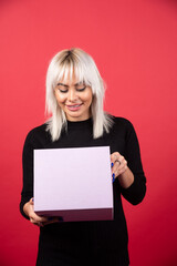 Young woman with present on a red background