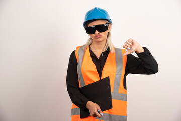 Female engineer in glasses making thumbs down on white background