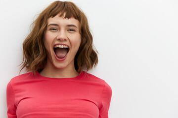 a funny, loudly screaming red-haired woman stands on a white background in a red T-shirt....