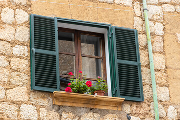 Fototapeta na wymiar window with flowers an green wooden shutters